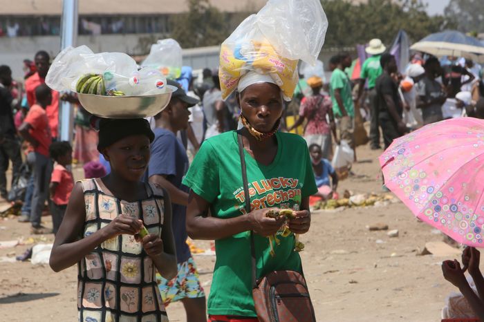 Một phụ nữ và con gái bán đồ giải khát trong khu chợ ở ngoại ô thủ đô Harare ngày 15/11. Ảnh: AP