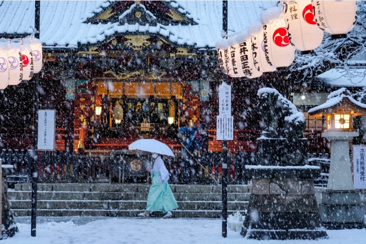 Một người phụ nữ đang đi ngang qua cổng một ngôi đền thờ Thần đạo Nhật Bản (Shinto) trong ngày tuyết rơi dày tại thủ đô Tokyo ngày 6/1/2022 - Ảnh: AP