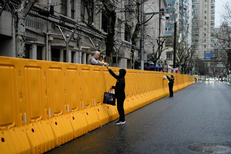 Người dân trao đổi thực phẩm và nhu yếu phẩm cần thiết qua hàng rào một khu phong tỏa ở Thượng Hải, Trung Quốc vào ngày 25/3. Ảnh: Reuters