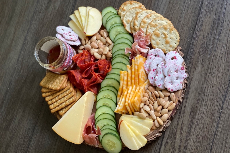 Một charcuterie board gồm: Phô mai, bánh quy, mứt, trái cây và hạt