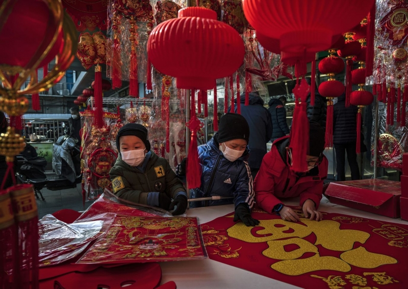 Những đứa trẻ đang chọn tấm biểu ngữ chữ Phúc và các biểu tượng may mắn tại một quầy bán đồ trang trí Tết Nguyên đán vào ngày 21/1, ở Bắc Kinh, Trung Quốc.