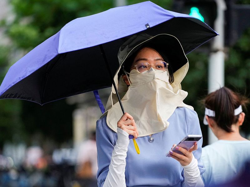 Theo dữ liệu từ Trung tâm Dự báo Môi trường Quốc gia Mỹ (NCEP), ngày 3/7 là ngày nóng nhất từng được ghi nhận trên toàn cầu. NCEP tính toán nhiệt độ trung bình toàn cầu vào ngày 3/7 là 17,01 độ C, vượt qua kỷ lục trước đó vào tháng 8/2016 là 16,9 độ C. Trong ảnh là một người phụ nữ trong trang phục kín mít khi ra đường ở Thượng Hải, khi thành phố này đang cảnh báo về đợt nóng gay gắt - Ảnh: Reuters
