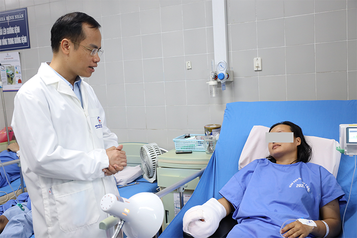 BS Hoàng Văn Hồng - Phụ trách Khoa Phẫu thuật tạo hình thẩm mỹ hỏi thăm người bệnh sau ca phẫu thuật - Ảnh: Bệnh viện Đại học Y Hà Nội