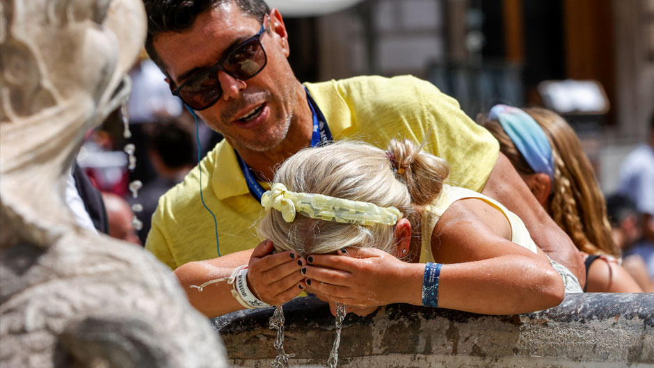 Một cô gái đang té nước vào mặt từ đài phun nước ở Rome, Italia để cố gắng hạ nhiệt trong một đợt sóng nhiệt ở Châu Âu - Ảnh: AP