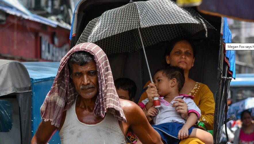 Một người mẹ che ô cho con để tránh nắng nóng ở Kolkata, Ấn Độ ngày 3/7/2023 - Ảnh: CNN