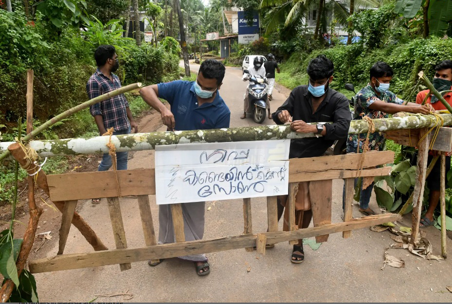 Người dân Ấn Độ gắn tấm biển ghi Khu vực ngăn chặn Nipah trên rào chắn được dựng lên tại một khu cách ly - Ảnh: Reuters