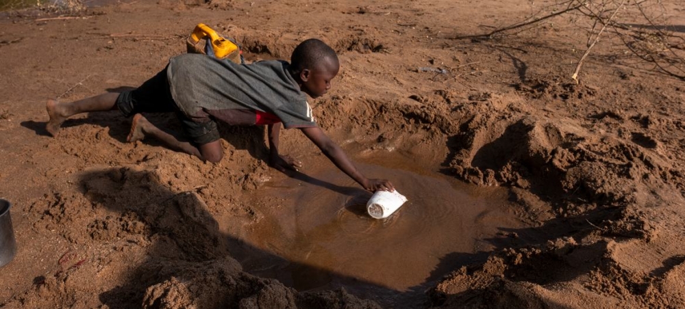 Một cậu bé đang hứng lượng nước còn ít ỏi từ một dòng sông khô cạn do đợt hạn hán nghiêm trọng ở Somalia - Ảnh: UNICEF