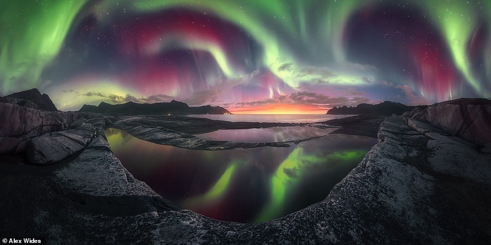Bức ảnh toàn cảnh độ ngoạn mục này, thể hiện cảnh mặt trời lặn trong màn trình diễn cực quang mạnh nhất trong năm 2023, được nhiếp ảnh gia Alex Wides chụp trên Đảo Senja ở Na Uy.