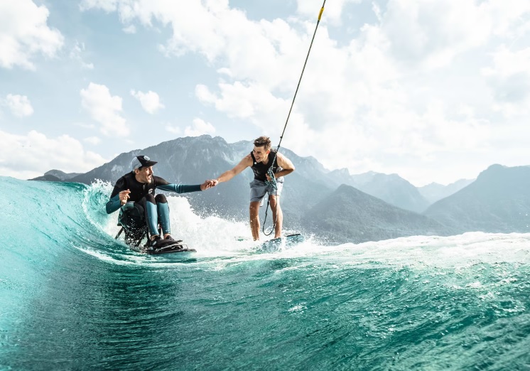 Khoảnh khắc đơn giản nhưng đầy ấm áp giữa Flo, vận động viên lướt ván bị liệt tứ chi đầu tiên thế giới và Markus Lahmer, bạn đồng hành, đang cùng nhau vui đùa với những con sóng. Ảnh của  Thibaut Lampe.
