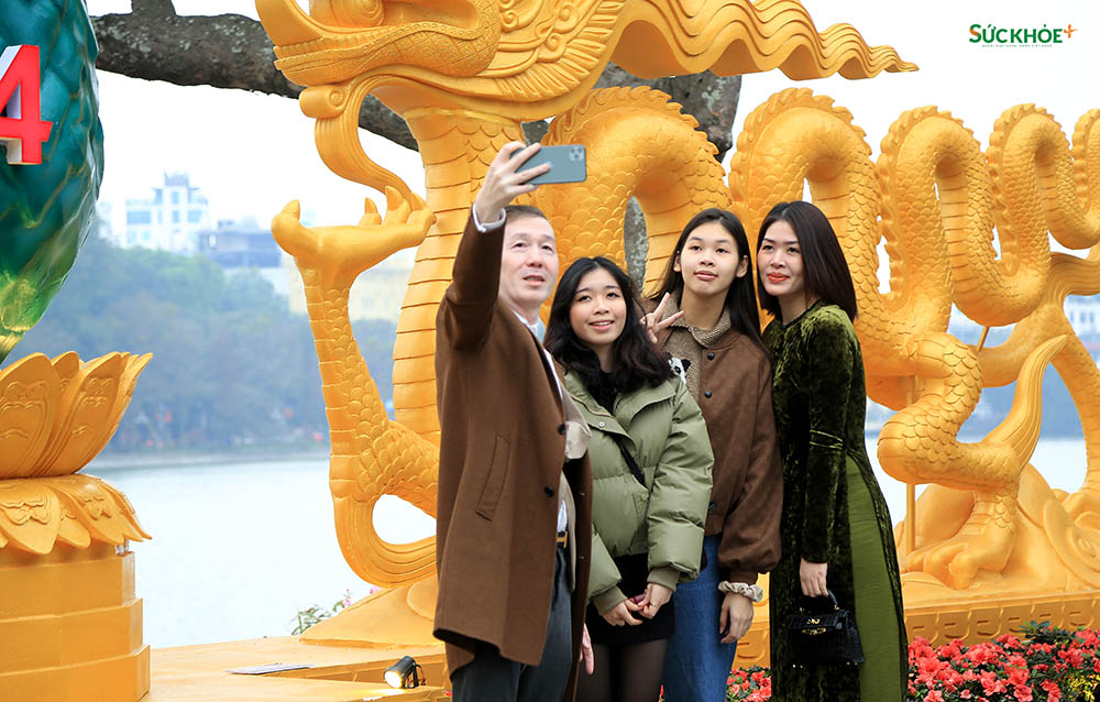 Một gia đình đang chụp ảnh selfie lưu giữ khoảnh khắc kỷ niệm trong ngày đầu năm mới Giáp Thìn trước biểu tượng con rồng tại Hồ Gươm, Hà Nội