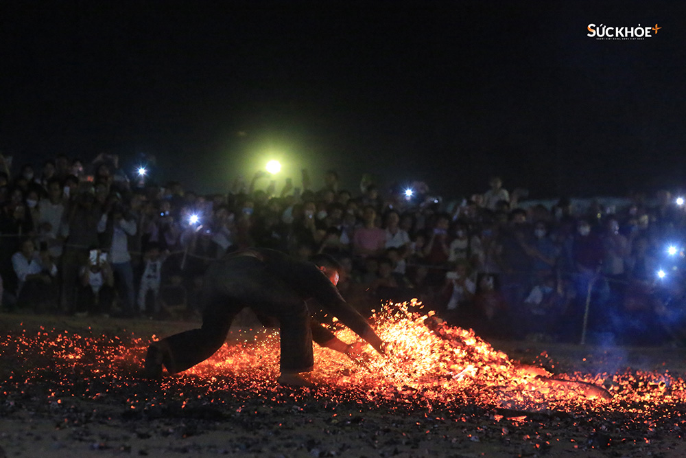Một chàng trai Pà Thẻn với đôi tay trần đang xới tung đống lửa đỏ rực trước sự hò reo của người dân và du khách