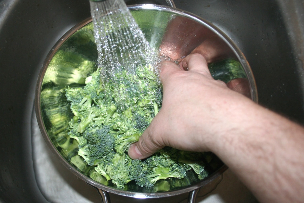 Rửa bông cải xanh dưới vòi nước chảy để làm sạch kỹ càng