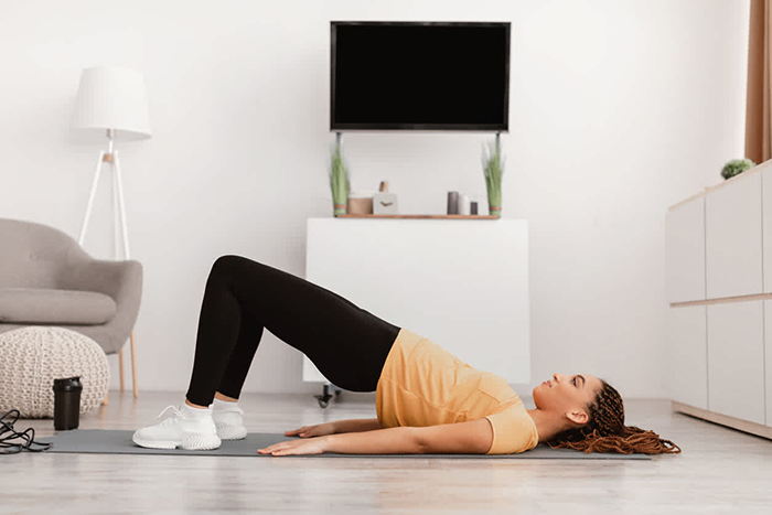 Woman-laying-on-yoga-mat-doing-bridges-at-home