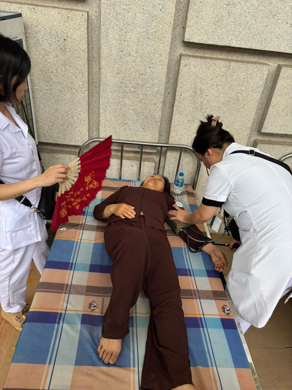 Nhân viên y tế đo huyết áp cho người dân bị hạ đường huyết, say nắng - Ảnh: MOH
