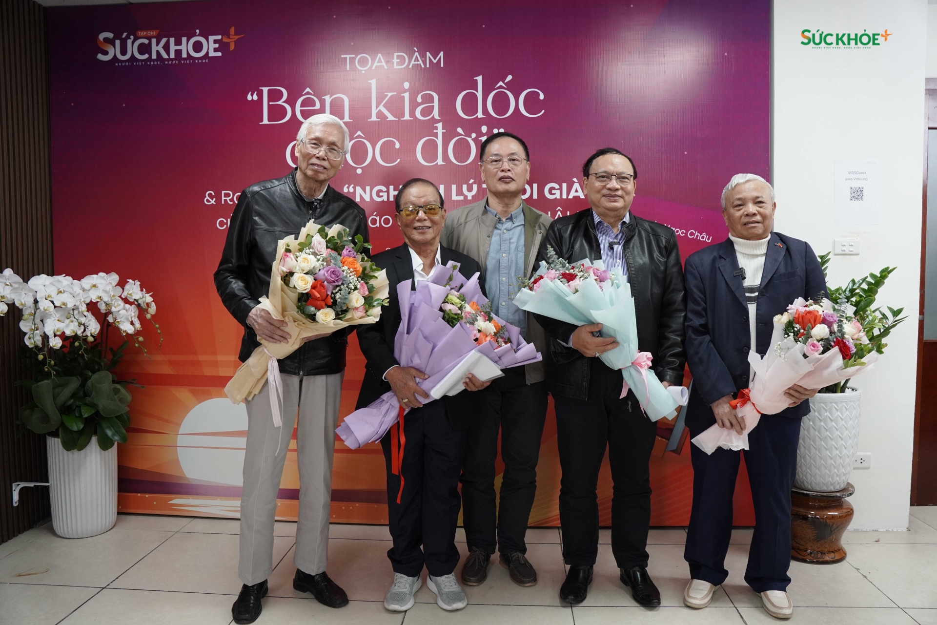 Nhà báo Vi Quang Đạo, Tổng biên tập Tạp chí Sức Khỏe+ tặng hoa và chụp ảnh lưu niệm với các diễn giả khách mời tại buổi Tọa đàm Bên kia dốc cuộc đời và ra mắt sách Nghịch lý tuổi già.