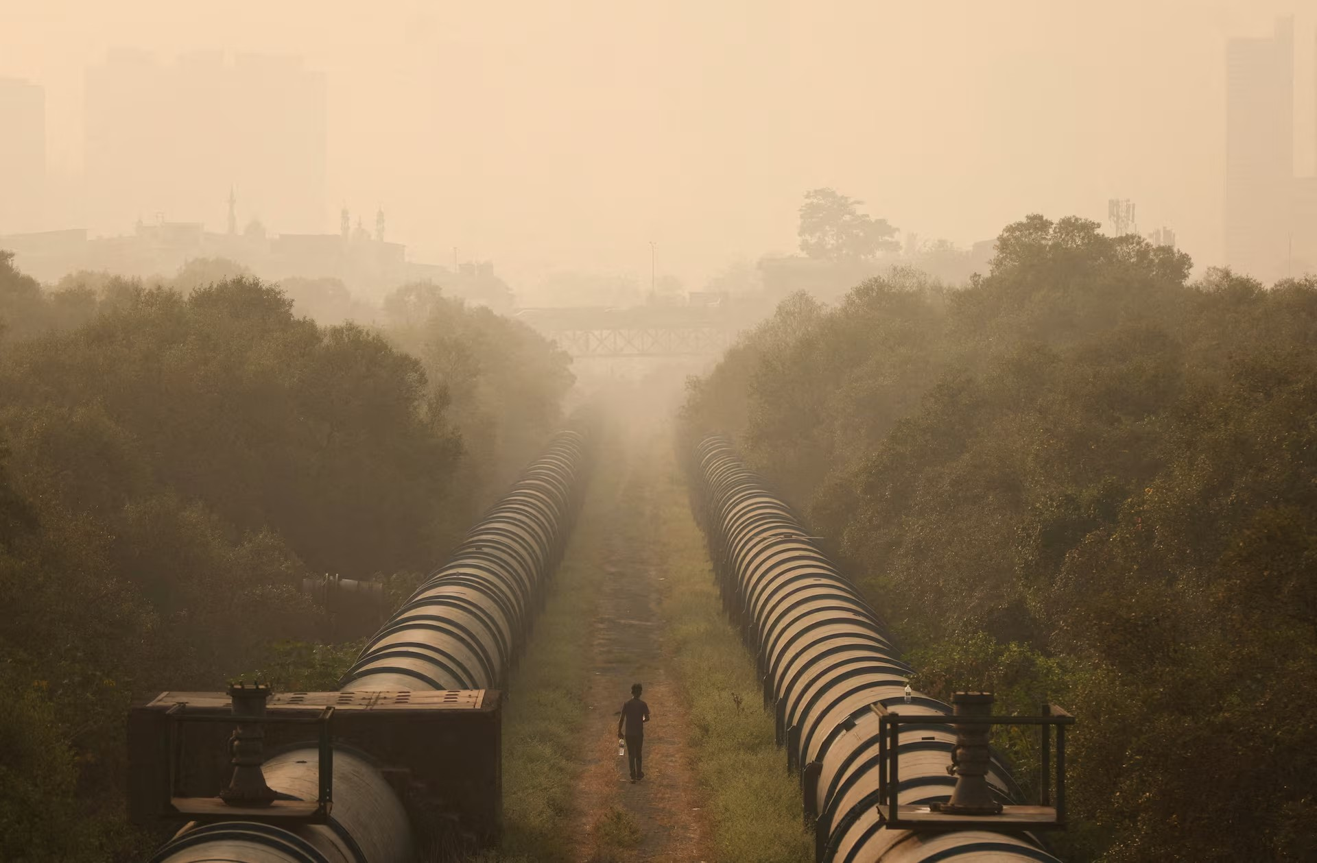 Một người đàn ông đang đi bộ giữa các đường ống dẫn nước vào một buổi sáng đầy khói bụi do ô nhiễm không khí, ở Mumbai, Ấn Độ, ngày 27/11 - Ảnh: Francis Mascarenhas