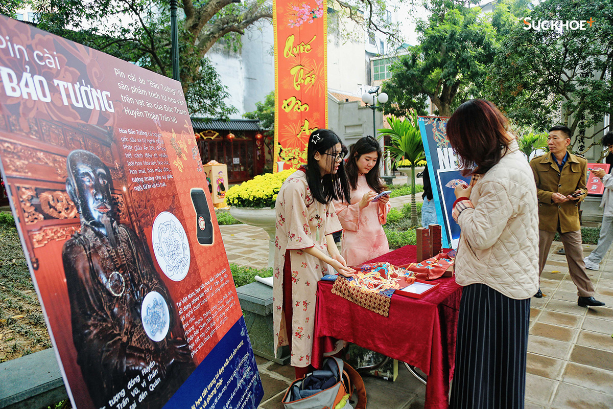 Một góc giới thiệu sản phẩm khăn quàng Huyền Quang và pin cài Bảo Tường - hai sản phẩm đặc trưng của đền Quán Thánh. Pin cài áo Bảo Tường là sản phẩm trích từ hoa văn trên vạt áo của Đức Thánh Huyền Thiên Trấn Vũ.