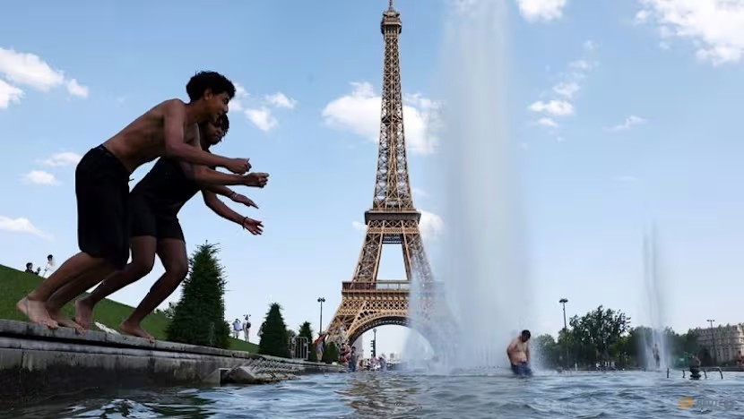 Người dân giải nhiệt tại Đài phun nước Trocadero cạnh Tháp Eiffel ở Paris khi nhiệt độ tăng cao trong đợt nắng nóng ảnh hưởng đến phần lớn nước Pháp, ngày 22/6/2026 - Ảnh: Reuters/Abdul Saboor