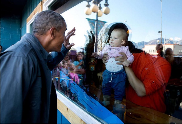 Tổng thống Mỹ vẫy chào một em bé qua khung cửa kính trên đường làm việc